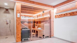Una sauna moderna con pareti in legno, una porta in vetro e una panca.