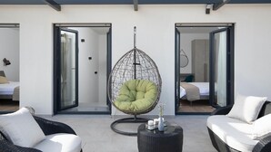 A modern outdoor seating area with wicker furniture, a hanging egg chair, and a small table with candles.