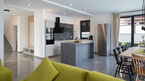 A modern kitchen with a central island, built-in appliances, and a dining area with a table and chairs.