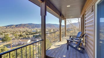 A wooden deck with a view of mountains and a house in the background.