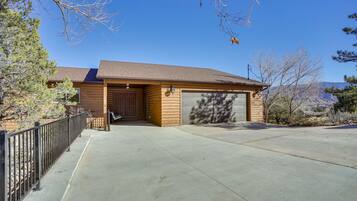 A single-story log cabin with a garage, a covered porch, and a clear view of the surrounding landscape.