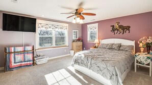 A bedroom with a bed, a ceiling fan, a TV, a dresser, a nightstand, and a window with curtains. - Charming Manchester Retreat w/ Patio & Fireplace! (Manchester)