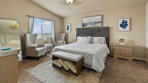 Une chambre à coucher avec un grand lit, une chaise, un bureau et une table de chevet.