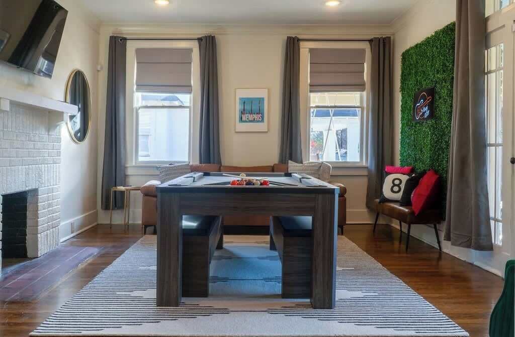 Um quarto aconchegante com mesa de bilhar, lareira e parede verde.