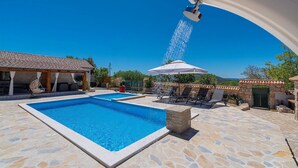A swimming pool with a stone-tiled deck, a covered seating area, and a view of the hills. - Awesome home in Polaca (Polaca)