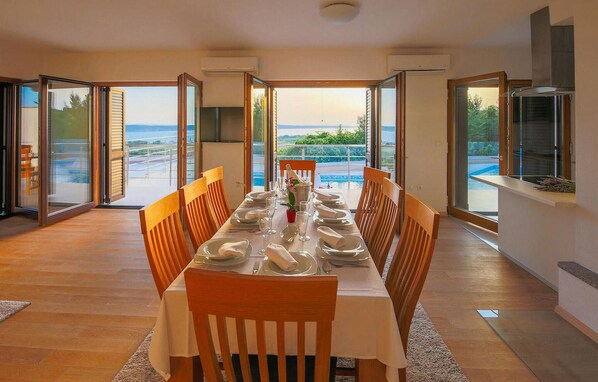 A dining room with a table set for six, large windows, and a view of a body of water.