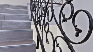 A staircase with a wrought iron railing featuring intricate designs.