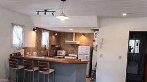 Une cuisine compacte dotée d’un îlot central, de tabourets de bar, d’un four à micro-ondes et d’un réfrigérateur.