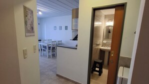 Un couloir mène à une salle à manger qui comprend une cuisine et une salle de bain.