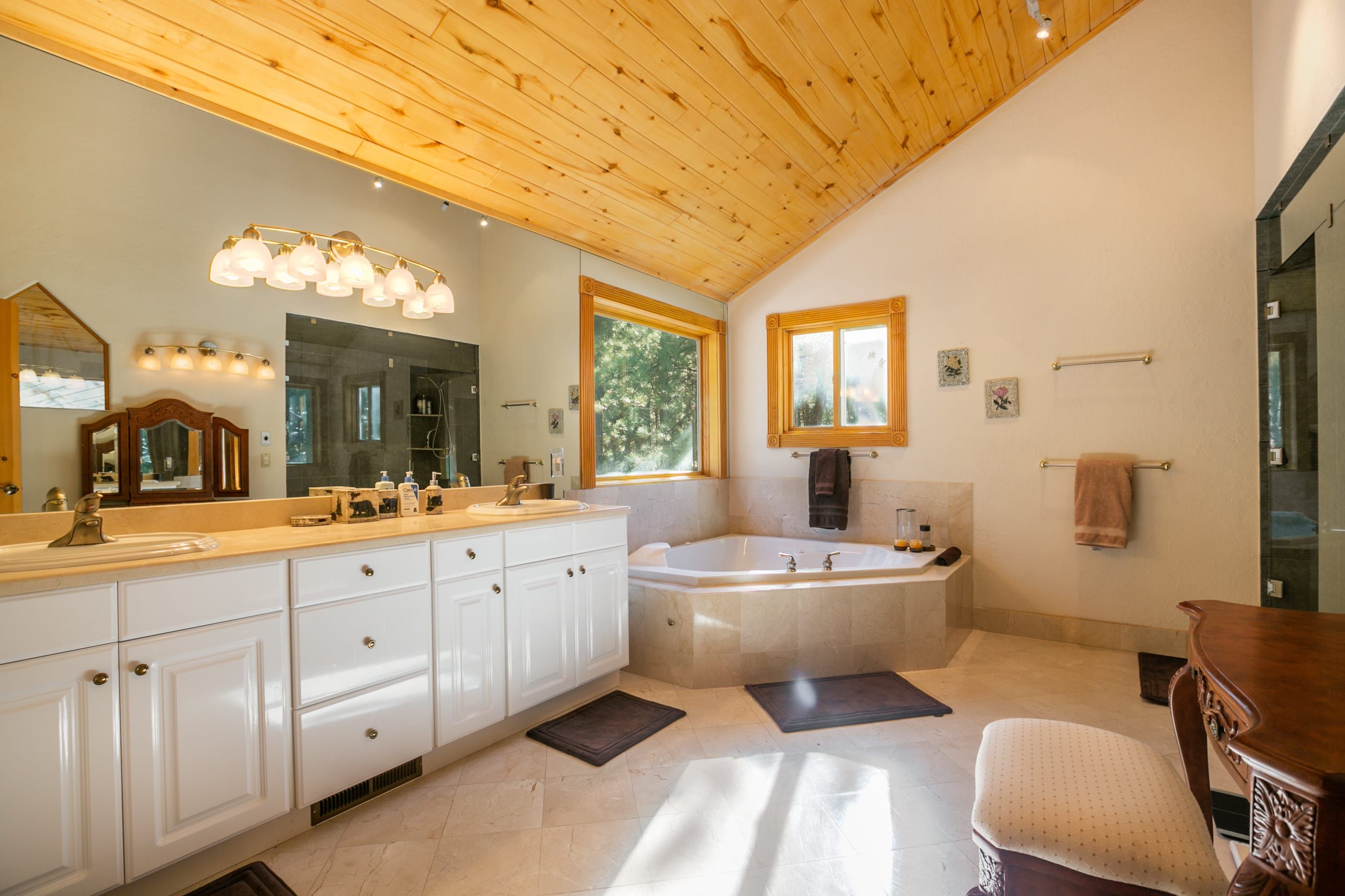 Une salle de bain spacieuse avec un grand meuble-lavabo, une baignoire sur pieds et un plafond en bois.