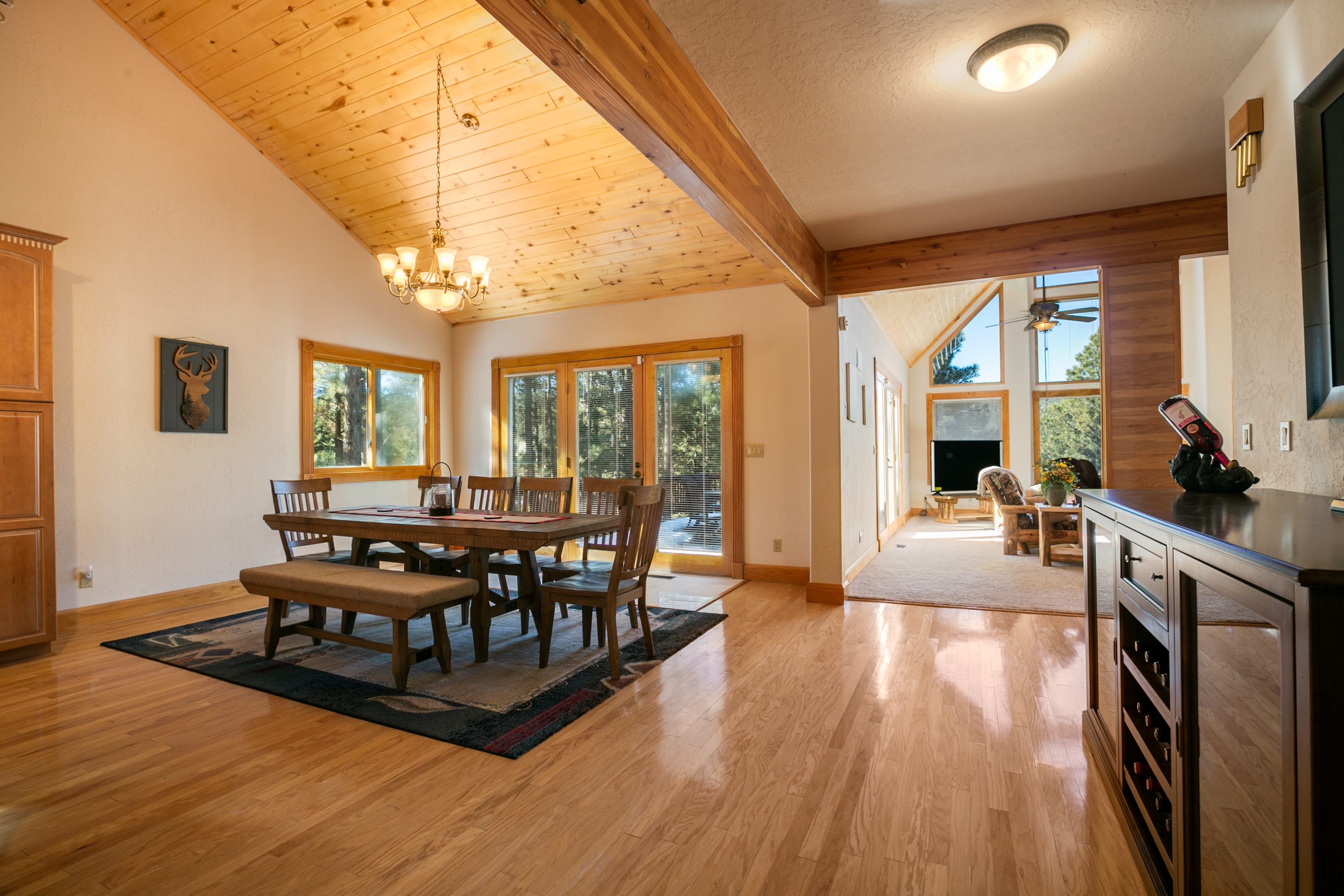 A spacious kitchen with wooden floors, a dining area with a large table and chairs, and a view of the outdoors through large windows.