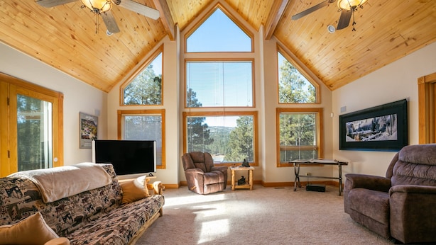 A spacious living room with high ceilings, large windows, and a cozy fireplace.