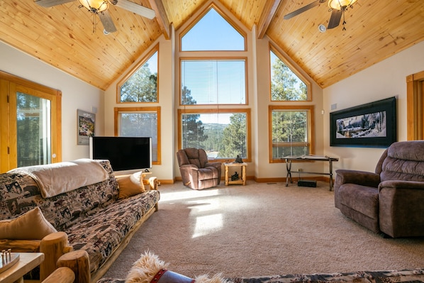A spacious living room with high ceilings, large windows, and a cozy fireplace.