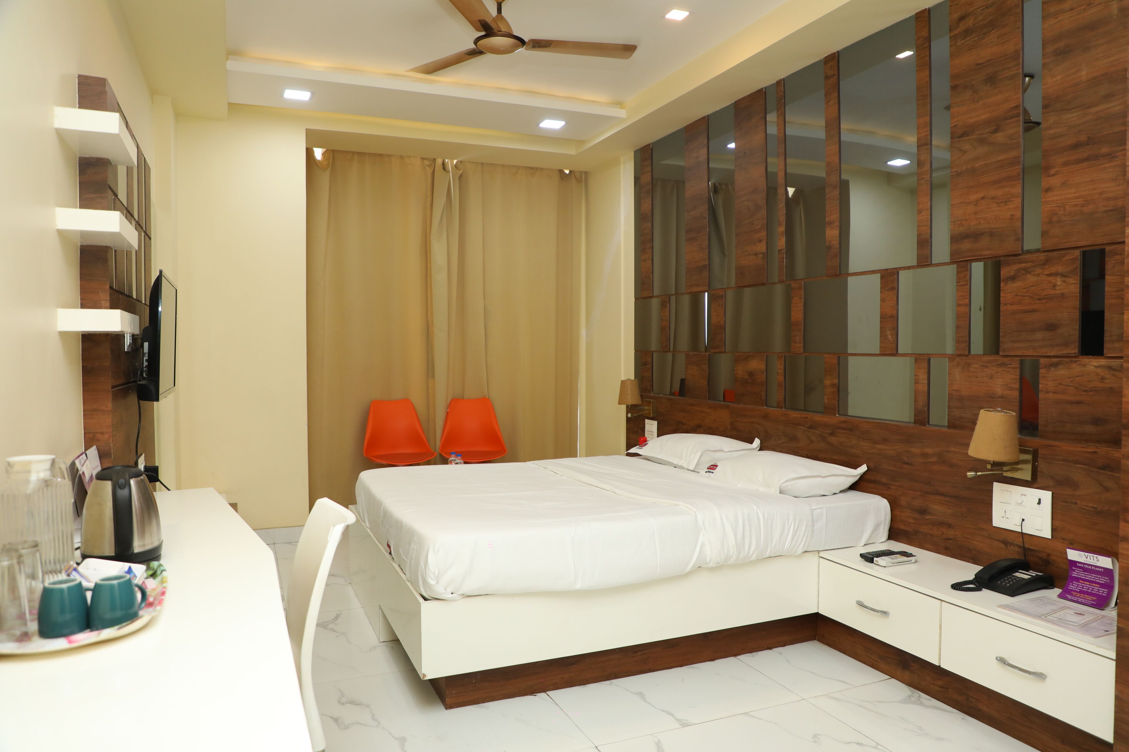 A modern hotel room with a bed, bedside table, and a large mirror.