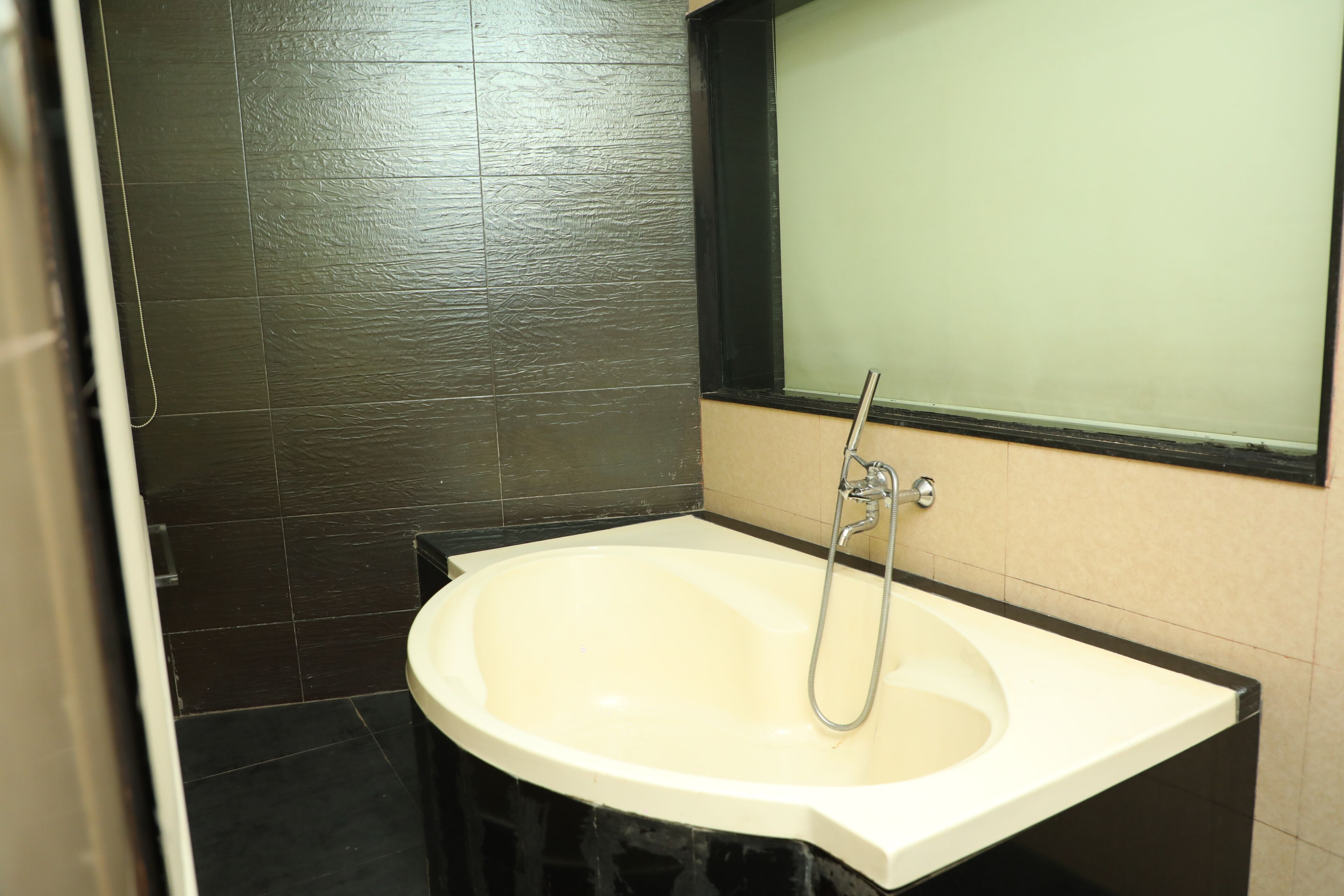 Un baño con lavamanos blanco, un espejo y paredes de azulejos oscuros.