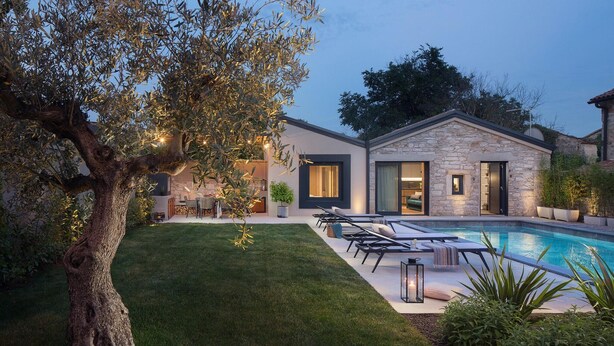 Una casa moderna con piscina, césped cuidado y mobiliario de exterior.