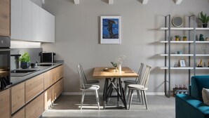 Una cocina moderna con armarios de madera, una mesa de comedor con cuatro sillas y una decoración minimalista que incluye una obra de arte enmarcada y una planta en un estante.