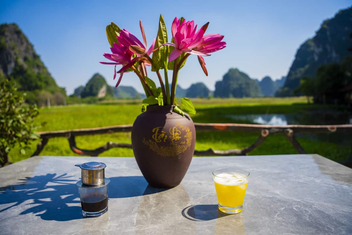 Et bord med kaffemaskine, et glas øl og en vase med blomster.