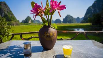 A table with a coffee maker, a glass of beer, and a vase with flowers.