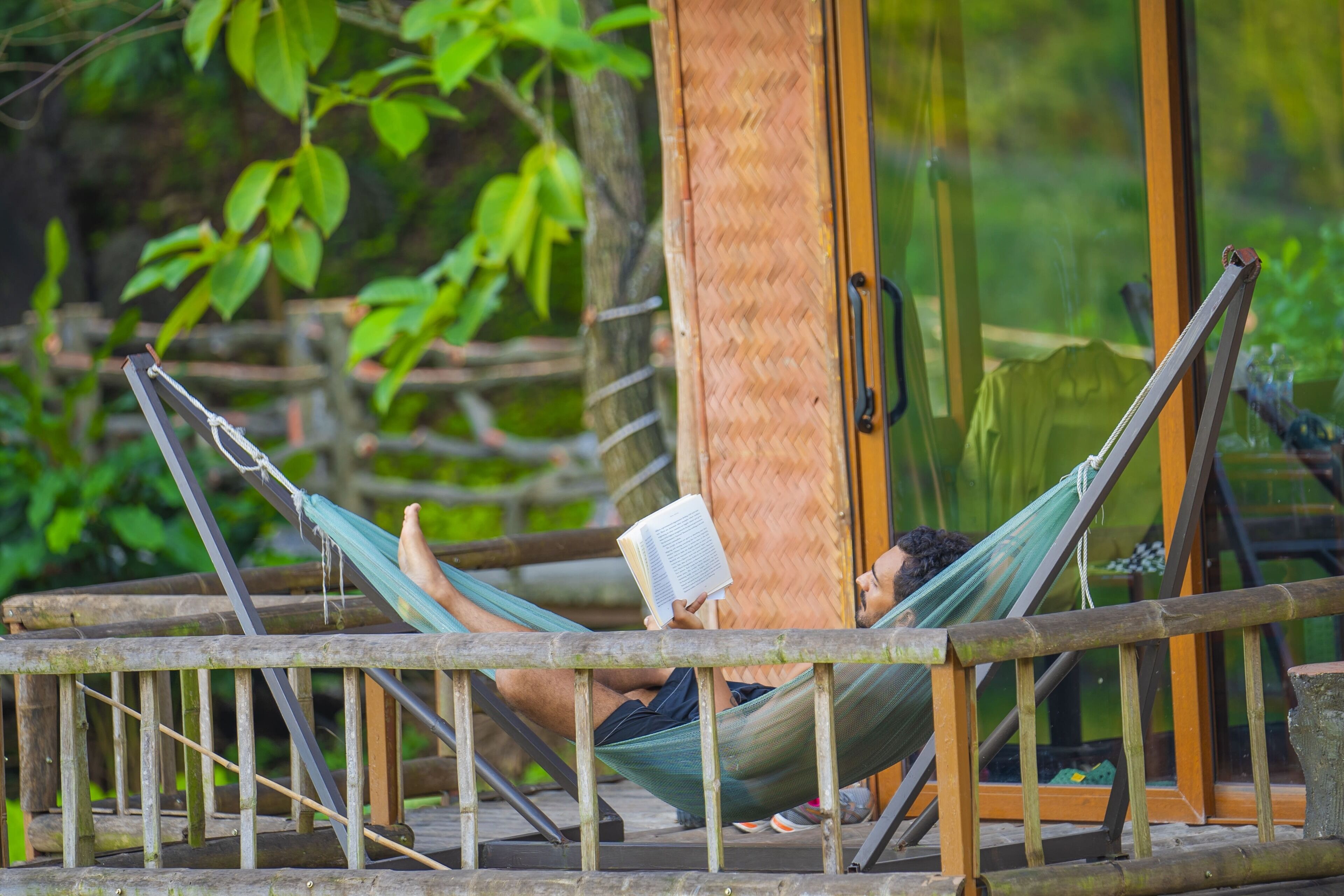 A hammock on a wooden deck with a glass door in the background.