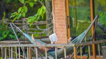 A hammock on a wooden deck with a glass door in the background.