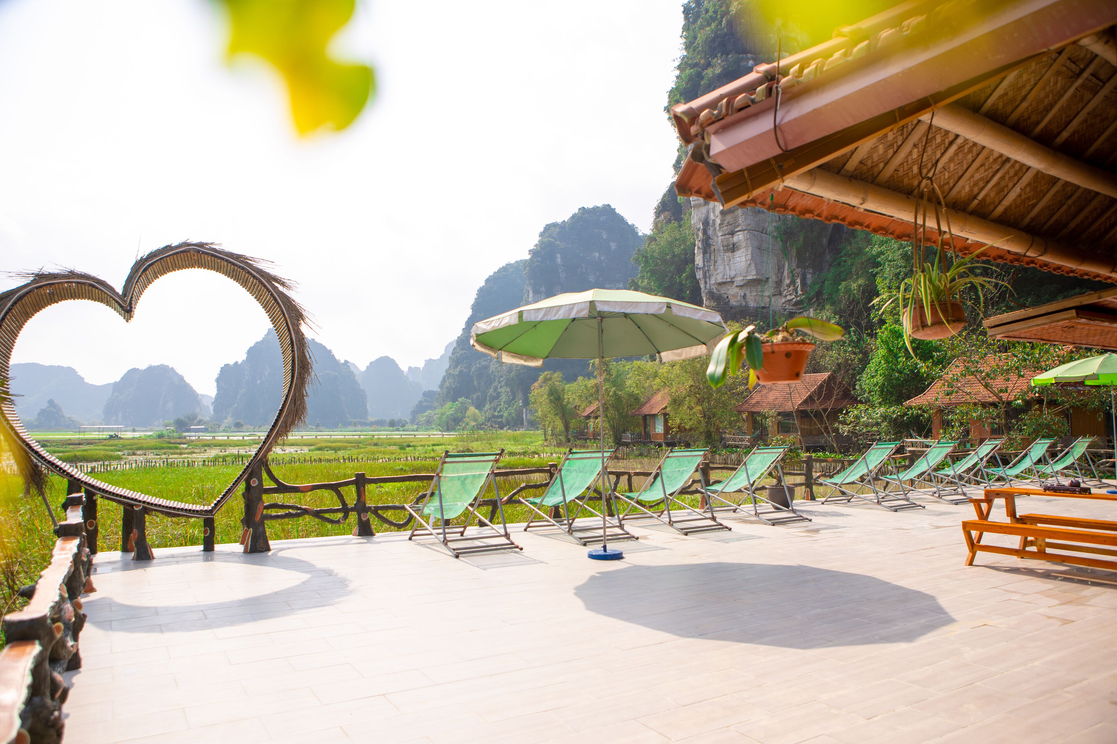 A terrace with lounge chairs and umbrellas overlooking a scenic valley.