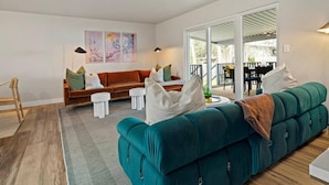 A modern living room with a teal sofa, a brown couch, and a dining area with a table and chairs. - Ultra Comfort + Style! HOT TUB & Fireplace! Two Living Rooms >10 min to Downtown & BSU! (Boise)
