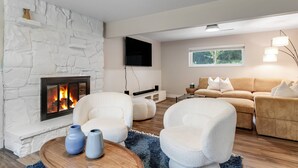 A modern living room with a stone fireplace, comfortable seating, and a large window. - Ultra Comfort + Style! HOT TUB & Fireplace! Two Living Rooms >10 min to Downtown & BSU! (Boise)
