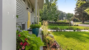 A residential house with a front porch, a large potted plant, and a well-maintained lawn. - Ultra Comfort + Style! HOT TUB & Fireplace! Two Living Rooms >10 min to Downtown & BSU! (Boise)