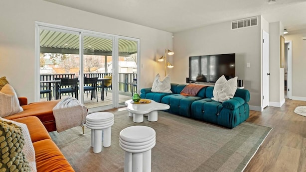 A modern living room with a teal sofa, orange armchair, and white coffee table. - Ultra Comfort + Style! HOT TUB & Fireplace! Two Living Rooms >10 min to Downtown & BSU! (Boise)