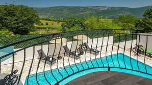 A poolside area with a view of mountains, outdoor seating, and a railing.