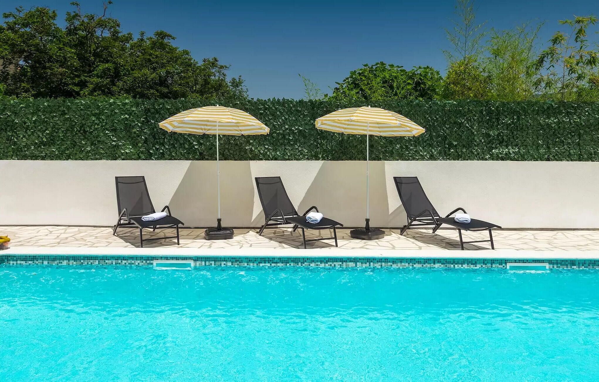 A poolside area with lounge chairs and striped umbrellas.