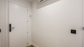 A hallway with a white door, a thermostat, and a light switch on the wall. - NEW loft one step away from SOL (P1B) (Madrid)