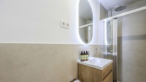 A modern bathroom with a wooden vanity, a white sink, and a glass shower enclosure.