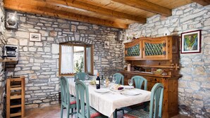 A rustic dining room with a stone wall, wooden ceiling, and a table set for four. - Beautiful home in Marcana (Marcana)
