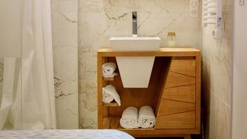 A bathroom with a marble wall, a wooden vanity, a sink, a mirror, and a shower curtain.