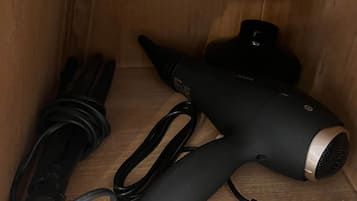 A wooden cabinet with a hair dryer and its power cord inside.