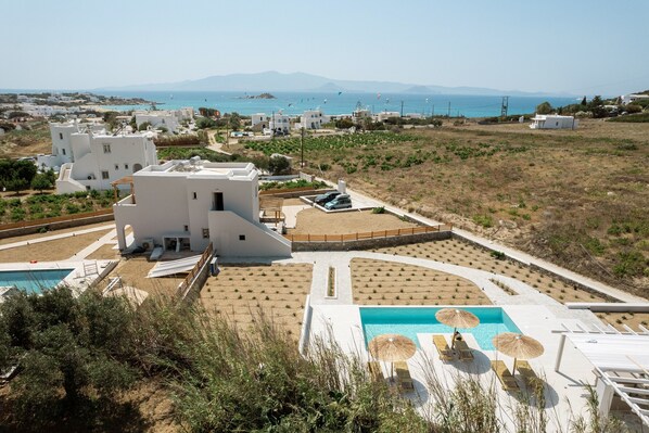 A resort with a pool area, multiple buildings, and a view of the sea.