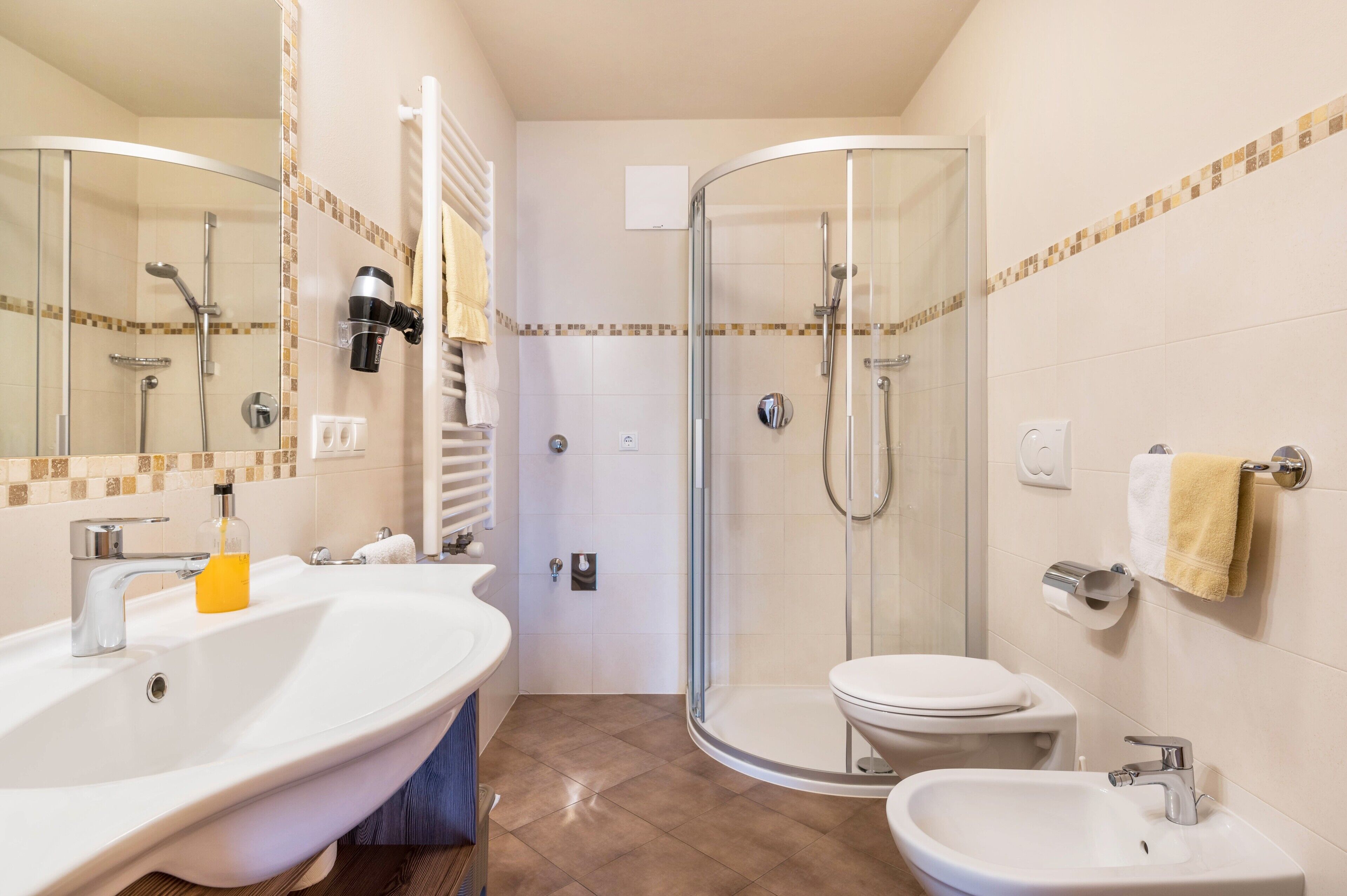 A bathroom with a glass-enclosed shower, a white sink, a toilet, and a bidet.