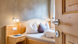 A wooden bed with pillows, a nightstand, and a wall-mounted light fixture in a room.