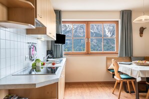 Une cuisine moderne dotée d’une grande fenêtre, de meubles en bois et d’un coin repas avec une table et des chaises.