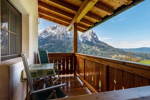 Un balcó de fusta amb taula i cadires, amb vista a un paisatge de muntanya.