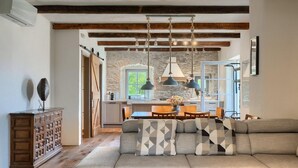 Un salón acogedor con sofá, vigas de madera, pared de piedra e iluminación colgante.