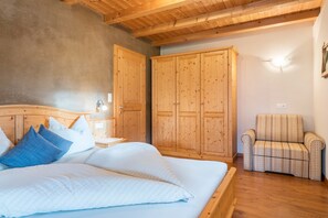 A bedroom with a wooden bed, a nightstand, a chair, and wooden wardrobes.