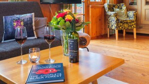 A cozy living room with a sofa, a table with a book, glasses, and a bottle.