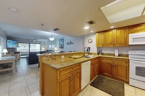 Una cocina moderna con encimeras de granito, gabinetes de madera y lavavajillas empotrado.