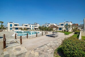 A modern hotel with a swimming pool, outdoor seating, and well-maintained landscaping.
