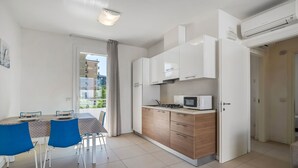 Une cuisine moderne avec des meubles blancs, un four à micro-ondes et un coin repas doté de chaises bleues.