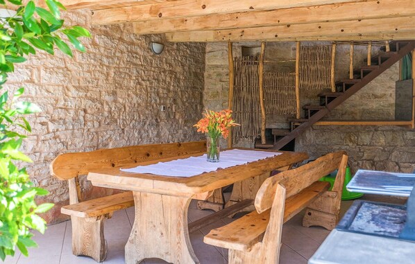 A rustic wooden bench and table set against a stone wall, with a vase of flowers on the table. - Pet friendly home in Pazin (Pazin)