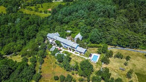 Vue aérienne d’un vaste domaine comprenant une maison principale, plusieurs dépendances et une piscine.